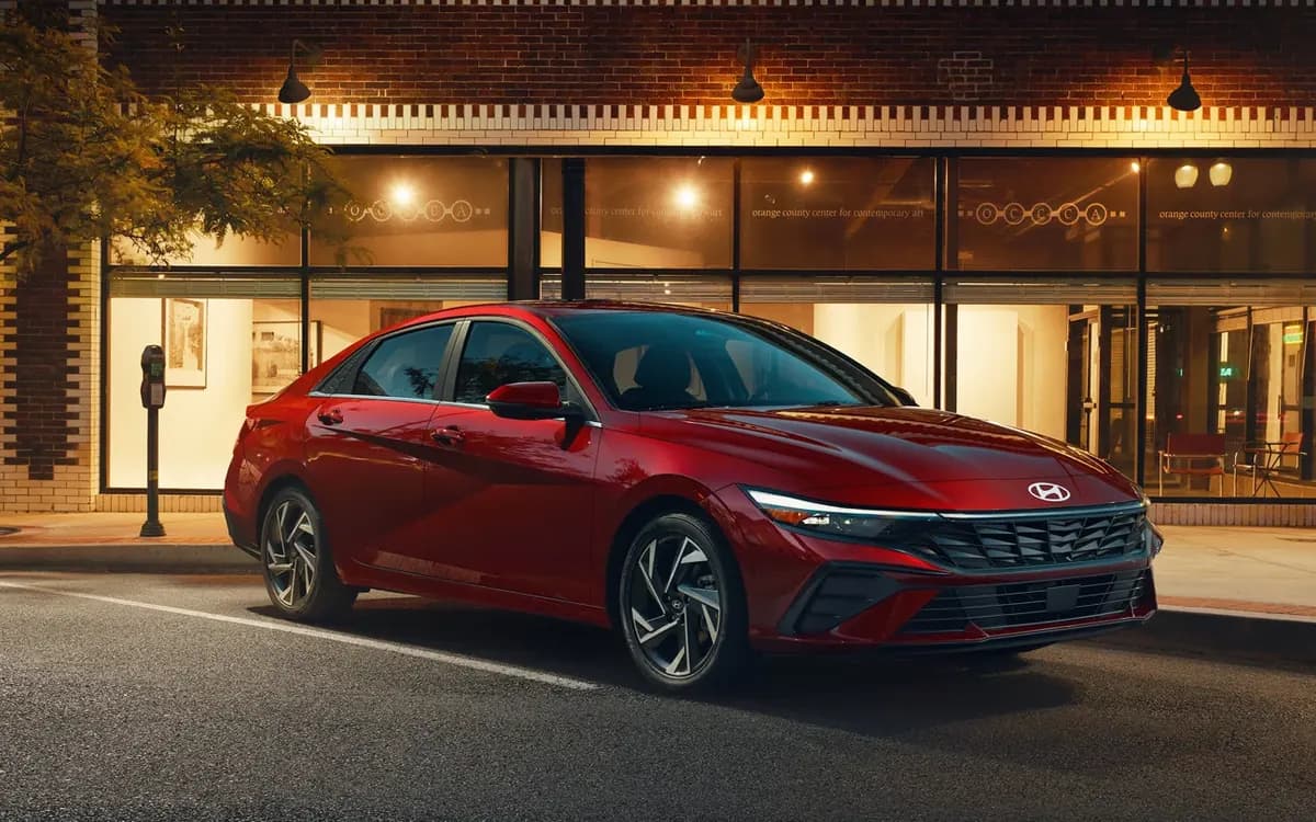 Hyundai Elantra sedan in red parked at night outside a lit storefront
